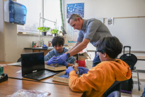 Teacher assisting two students in a science lab