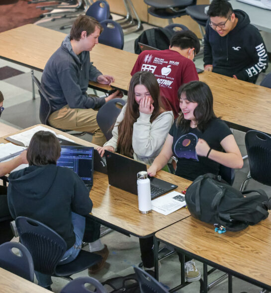Students laughing at something on a laptop