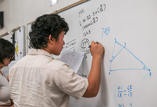 Student practicing math on the class white board